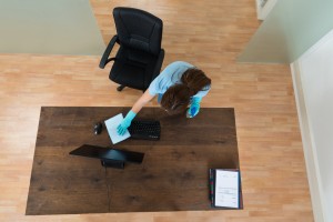 High Angle View Of Young Woman Cleaning Keyboard At Desk In Office